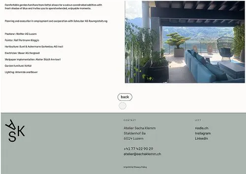 Modern outdoor terrace with blue garden sofa and greenery overlooking a mountain landscape under a covered patio.