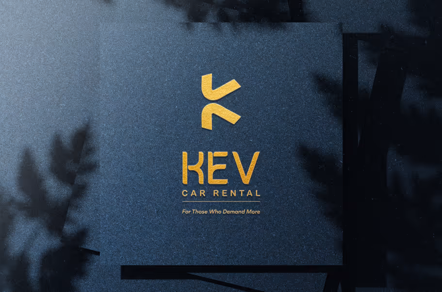 Gold embossed logo and text reading KEV Car Rental with tagline 'For Those Who Demand More' on a textured dark blue background.